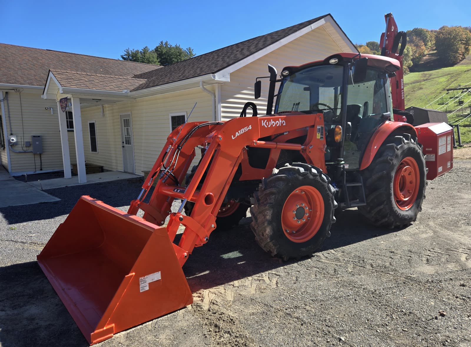 The town's new orange Kubota tractor with a front loader bucket, parked outside Town Hall
